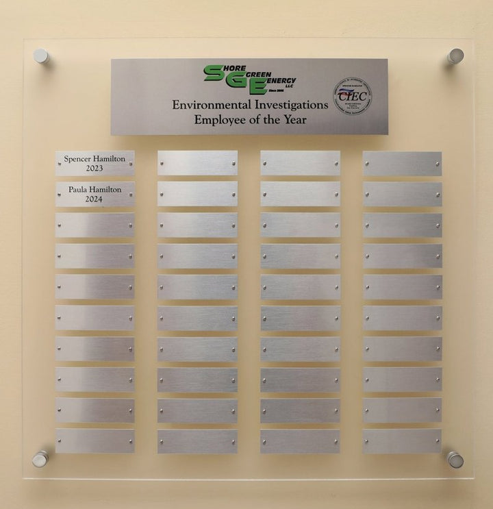 A  23 by 23 inch Frosted Acrylic Perpetual plaque with Header Plate, Logo and 40 Individual Silver Aluminum name plates for recognizing employees or winners mounted on a wall. 