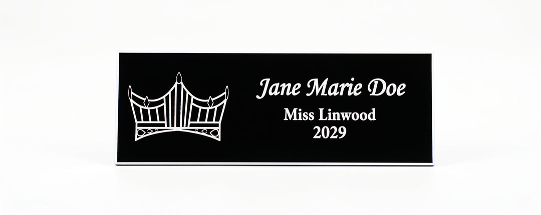 A rectangular black Name Badge  with white engraved text reading &