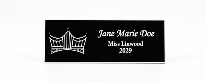 A rectangular black Name Badge  with white engraved text reading &