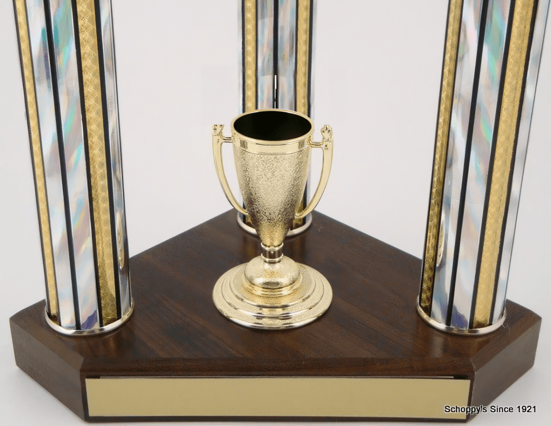 A trophy cup centerpiece on a dark wood base with two iridescent glass columns accented by gold trim, shown against a plain white background.