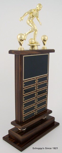 Side view of A large Soccer Perpetual Trophy by Schoppy's. The trophy features a Large 8 inch Soccer Figure in a kicking position and comes with decorative soccer ball trim. The front of the base displays a large black laser-engraved heading plate, accompanied by 12 smaller individual plates for recording past winners